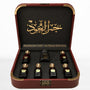Al Mayas Selection Perfume Gift Box by Jamr Al Oud, open burgundy leather box with six perfume bottles, one dokhoon jar and gold corner details.